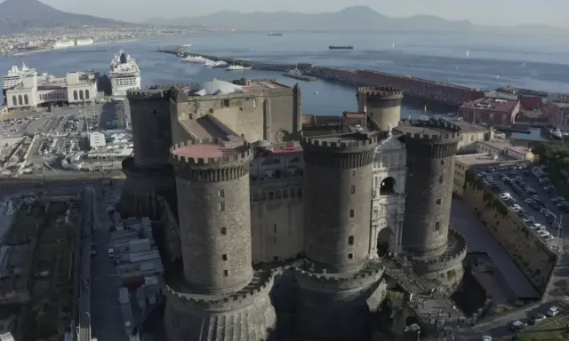 Maschio Angioino con la Cappella Palatina, imponente castello medievale a Napoli, affacciato sul mare con il Vesuvio sullo sfondo.