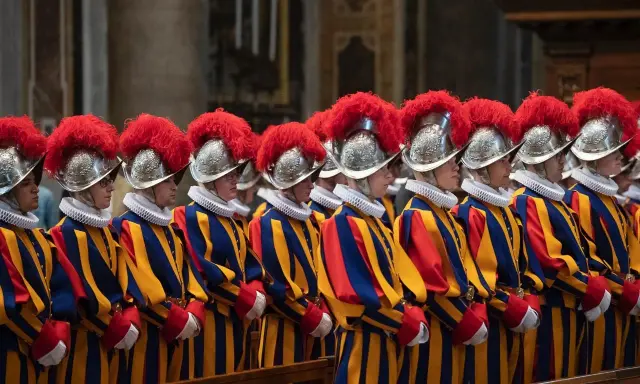 Guardie svizzere in divisa colorata, con elmi piumati, spiegano perchè il Papa ha le guardie svizzere: sono la sua protezione storica.
