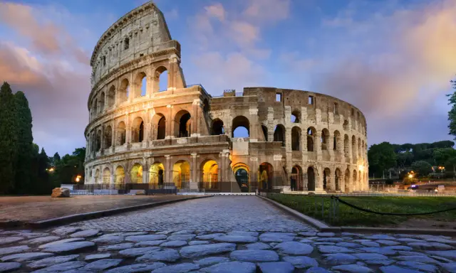 Il Colosseo, uno dei monumenti famosi a Roma, illuminato al tramonto con un cielo nuvoloso.