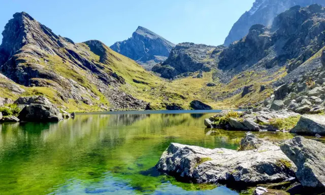 Lago alpino dalle acque smeraldine, incastonato tra montagne scoscese e verdi pendii. Un angolo di pace nell'Italia del Nord.