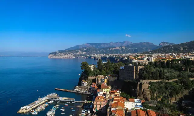 Vista panoramica di Sorrento: cosa vedere a Sorrento in un giorno, con il porto, le case colorate a picco sul mare e i monti sullo sfondo.