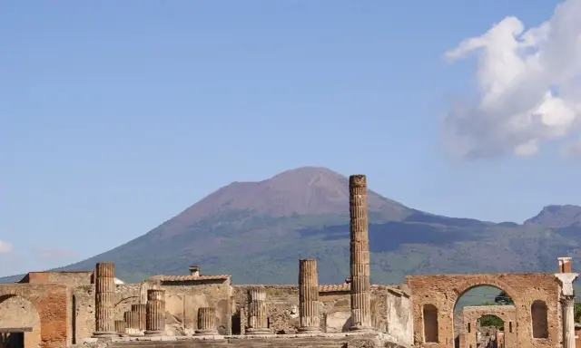 Rovine di Pompei con il Vesuvio sullo sfondo. Un'idea per cosa visitare a Pompei in un giorno, tra colonne antiche e storia millenaria.