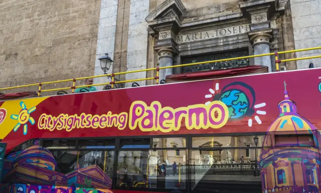 Autobus turistico rosso con scritta "City sightseeing Palermo". Un modo comodo per muoversi a Palermo e ammirare i monumenti.