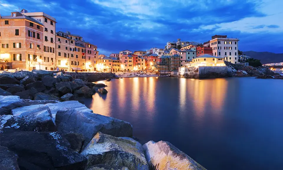 Case colorate illuminate sul mare calmo, la **riviera ligure di levante** incanta al crepuscolo.
