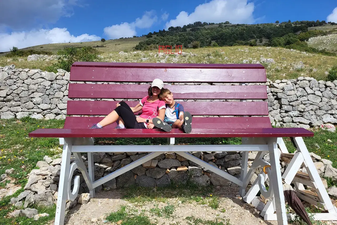 Mamma e figlio si godono una pausa su una panchina panoramica, perfetta per le gite di 1 giorno da Roma.