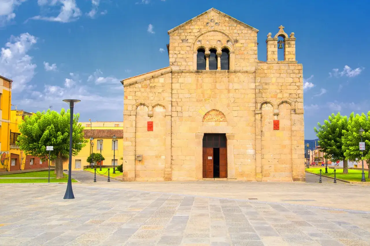 Piazza del centro di Olbia con la Basilica di San Simplicio, un gioiello romanico sotto un cielo azzurro.