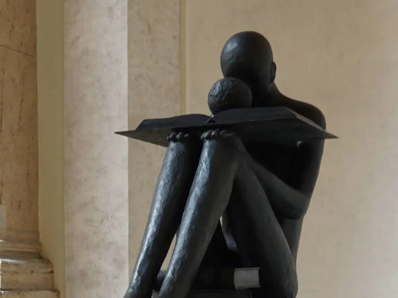 Statua di una figura che legge un libro, immersa nella conoscenza a tutto spiano.