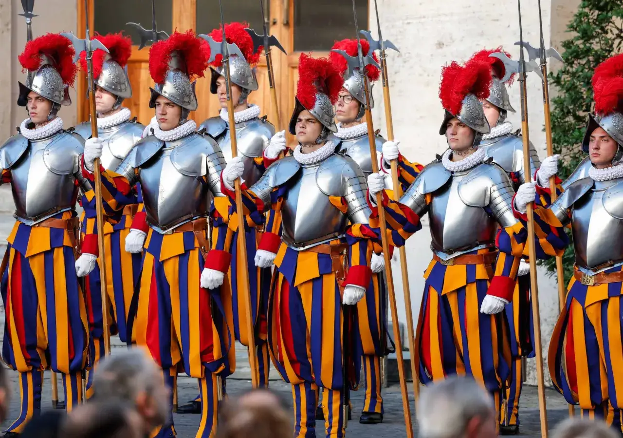 Guardie svizzere in divisa storica, con elmi piumati e alabarde, pronte a difendere la Città del Vaticano.