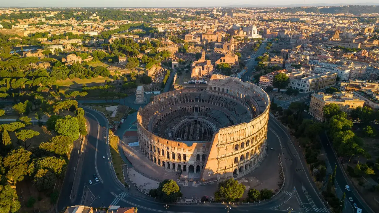 Vista aerea del Colosseo, un simbolo di Roma e patrimonio dell'UNESCO, illuminato dalla luce dorata del tramonto.