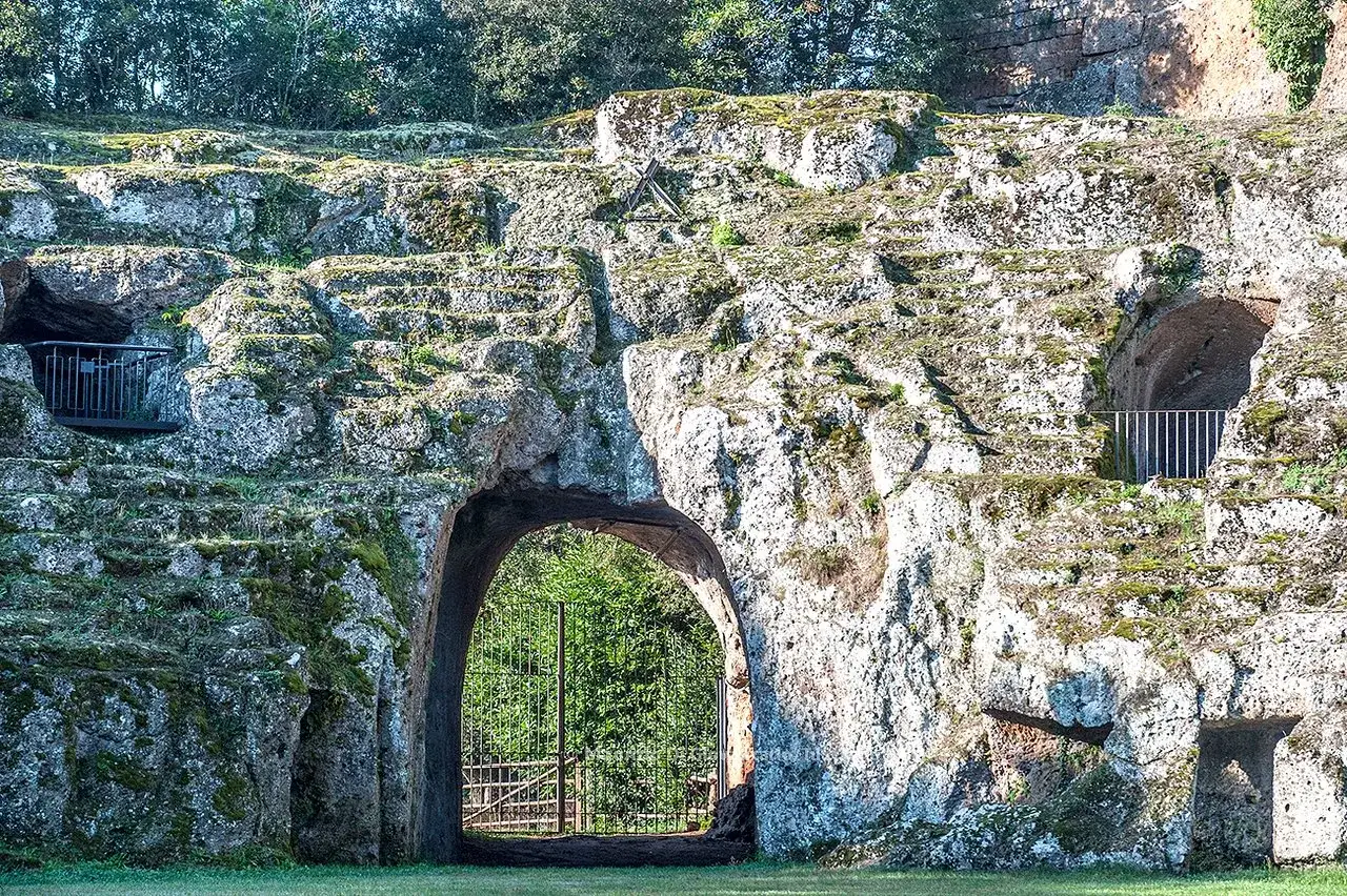 Antico borgo di Sutri: anfiteatro scavato nella roccia con gradinate, grotte e un arco d'ingresso.