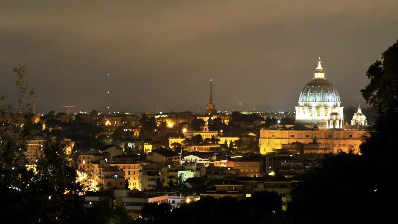 La cupola di San Pietro illumina la roma di notte, con un panorama di luci che si estende all'orizzonte.