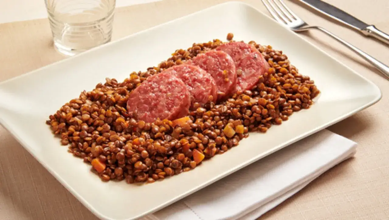 Piatto di lenticchie con fette di salame. Le lenticchie, con il loro significato simbolico di abbondanza, sono un piatto tradizionale.