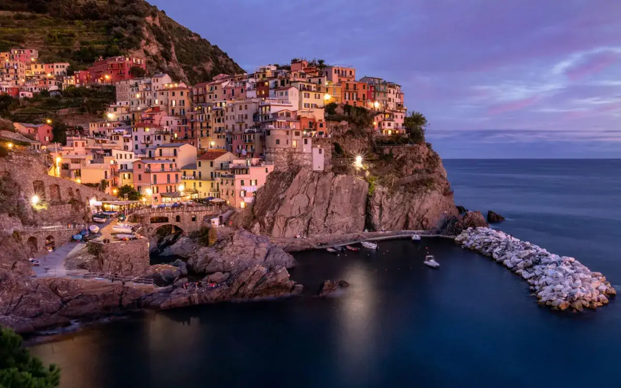 Colorate case aggrappate alla scogliera, un incantevole levante città sul mare al crepuscolo.