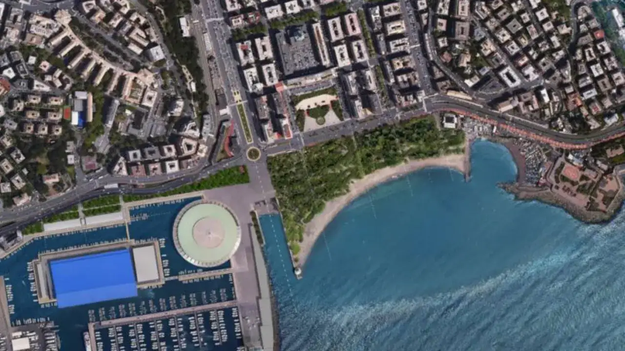 Vista aerea del Porto Antico di Genova, un progetto di Renzo Piano, con il mare blu, la spiaggia e gli edifici circostanti.