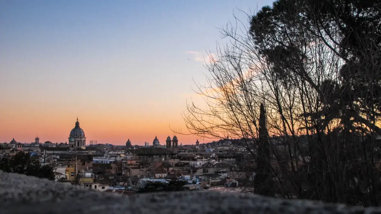 Un magico pincio roma tramonto con cupole illuminate dal sole calante e silhouette di alberi.
