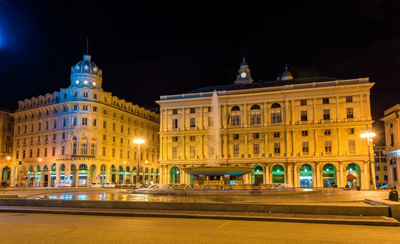 Fontana illuminata e palazzi storici, un'atmosfera magica che cattura la genova vita notturna.