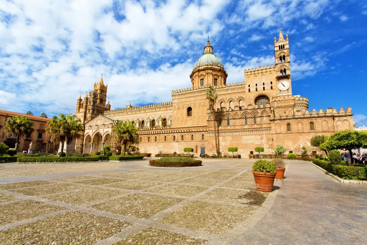 La Cattedrale di Palermo, un capolavoro di stili architettonici diversi, si erge maestosa sotto un cielo azzurro e nuvoloso.