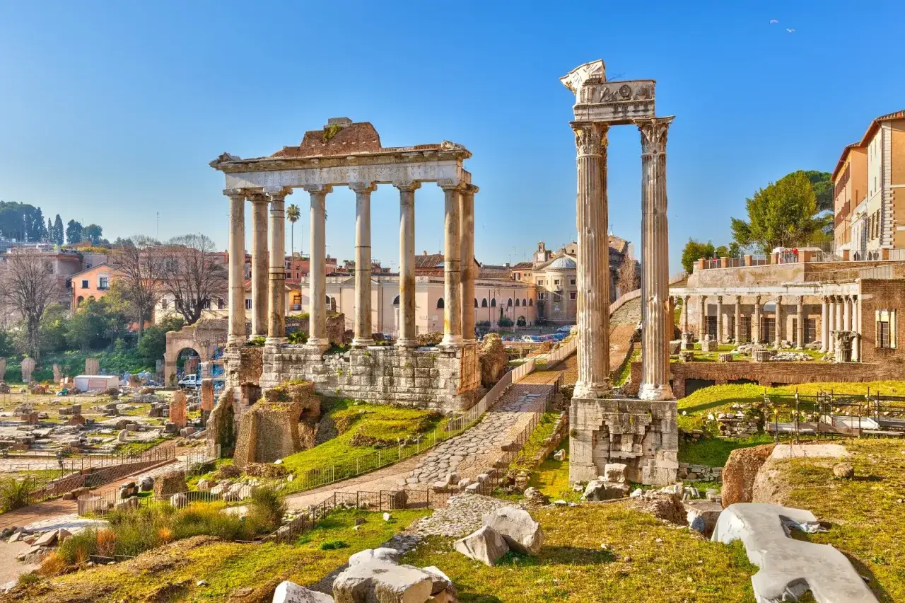Antiche rovine del Foro Romano con colonne imponenti e un cielo azzurro.