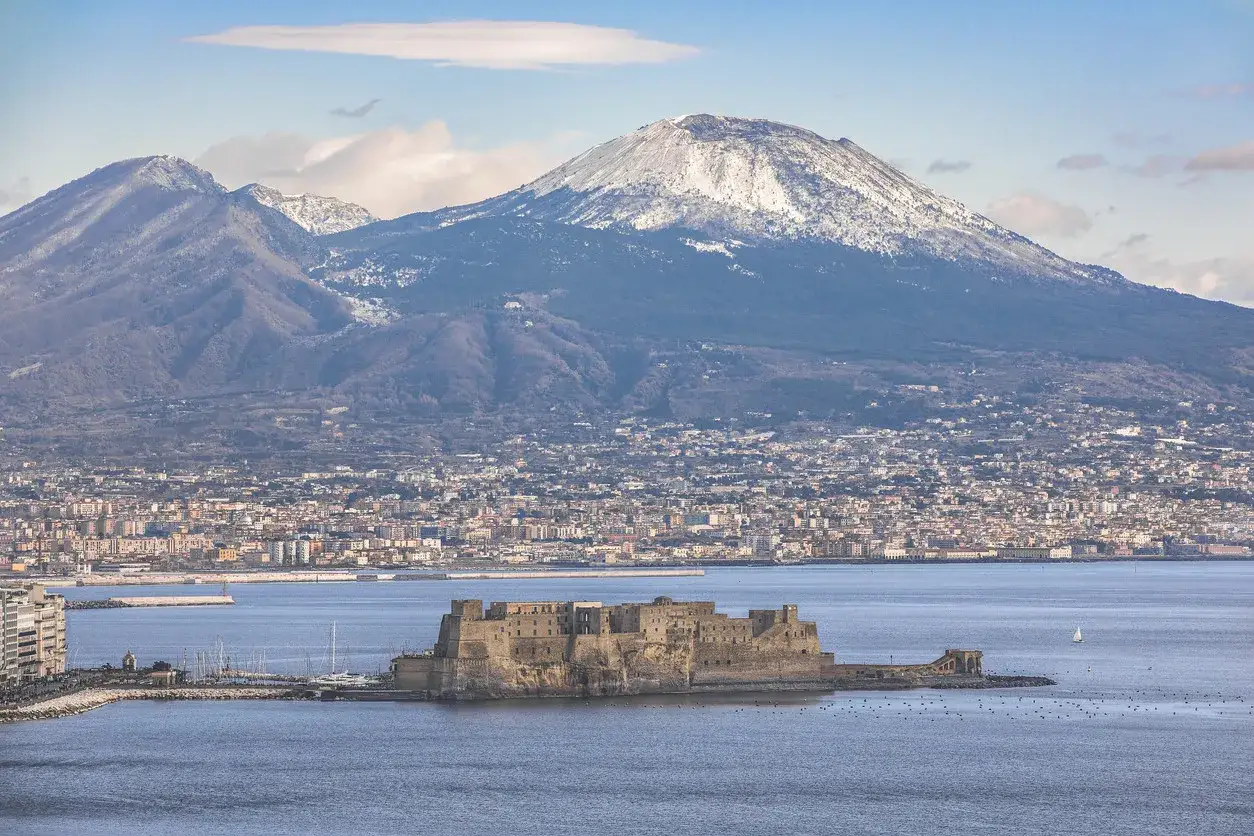 Castel dell'Ovo a Napoli a gennaio, con il Vesuvio innevato sullo sfondo. Un paesaggio suggestivo e freddo.