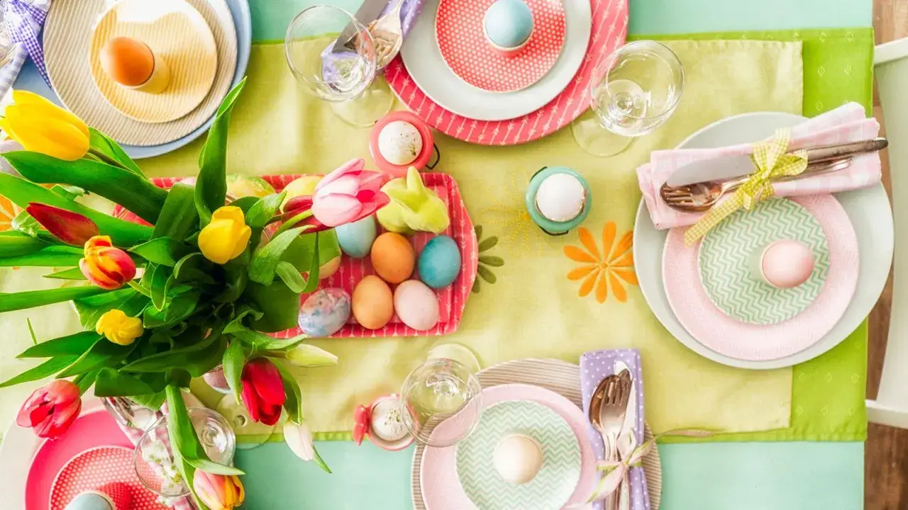 Tavola apparecchiata per Pasqua con tulipani colorati, uova dipinte e piatti a tema. Idee su cosa fare a Pasqua per un pranzo speciale.