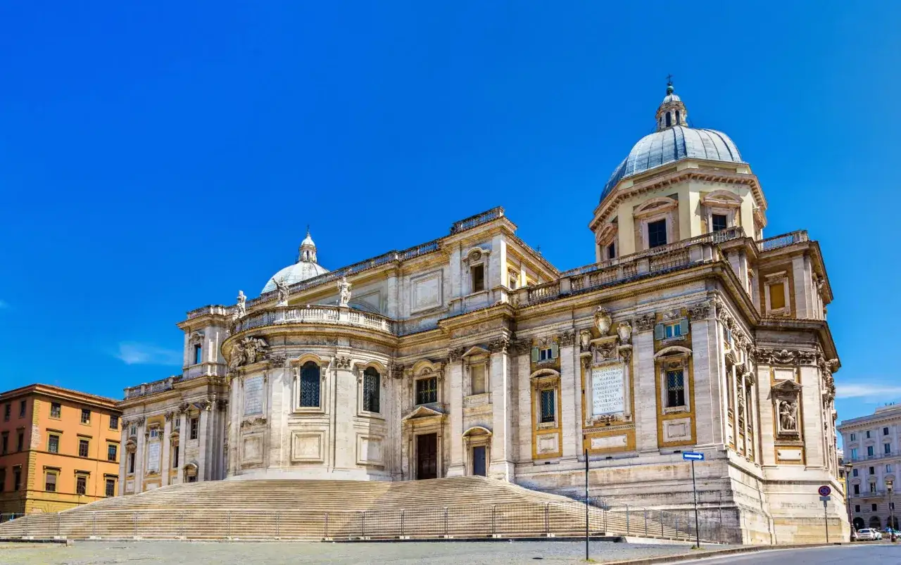 Magnifica facciata di una delle chiese a Roma, con imponenti scalinate e cupole sotto un cielo azzurro.